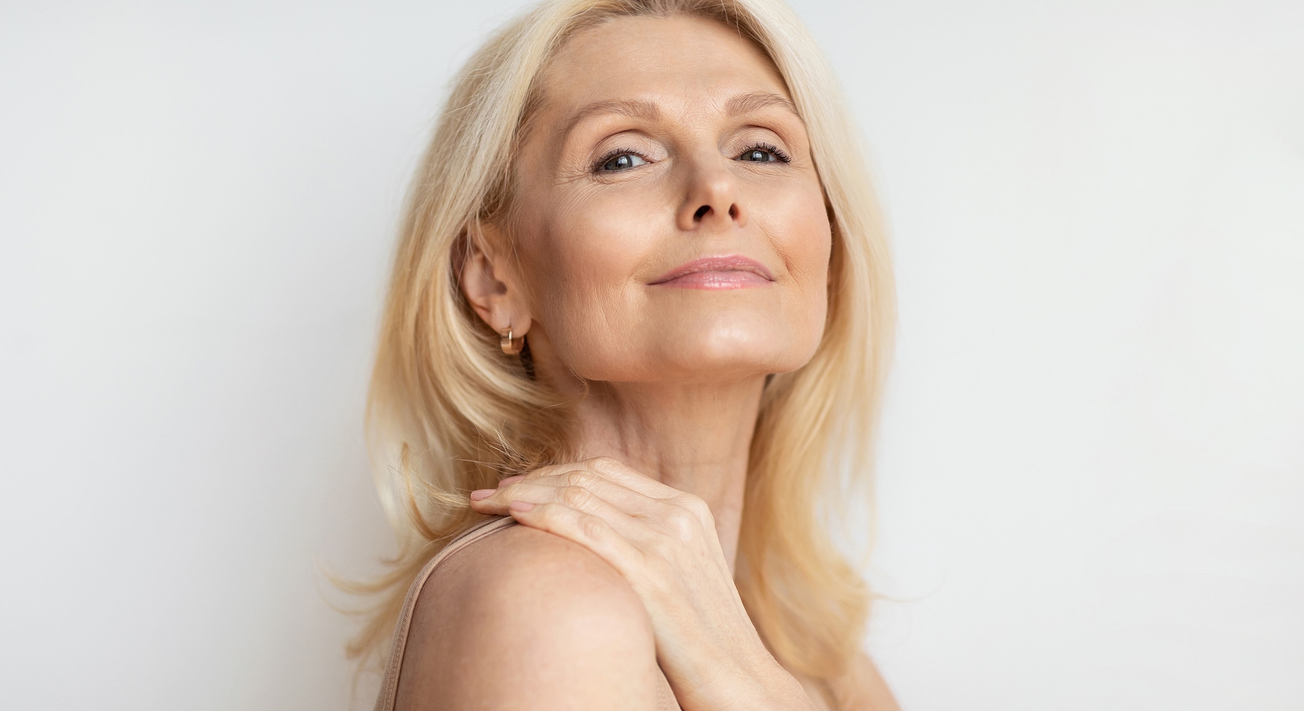 Mature woman smiling with soft, natural makeup.