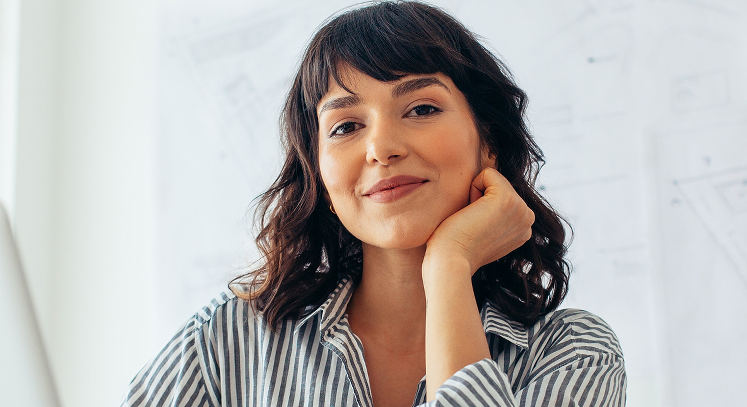 Smiling woman with curly hair in striped shirt.