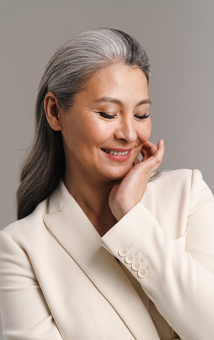 Smiling woman with gray hair in blazer.