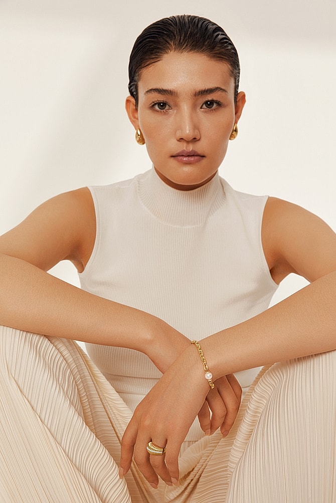 Model wearing elegant jewelry and casual attire.