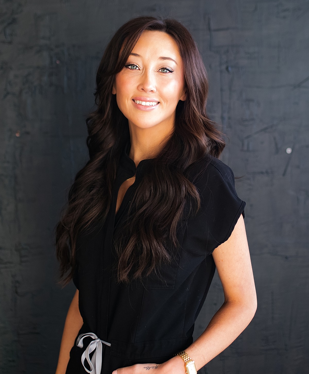 Smiling woman with long hair in black top.