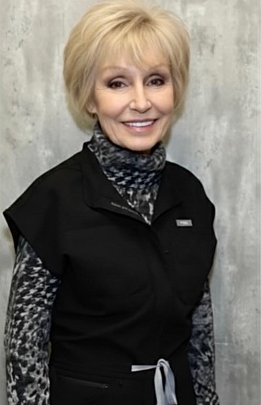 Smiling woman in professional attire against gray background.
