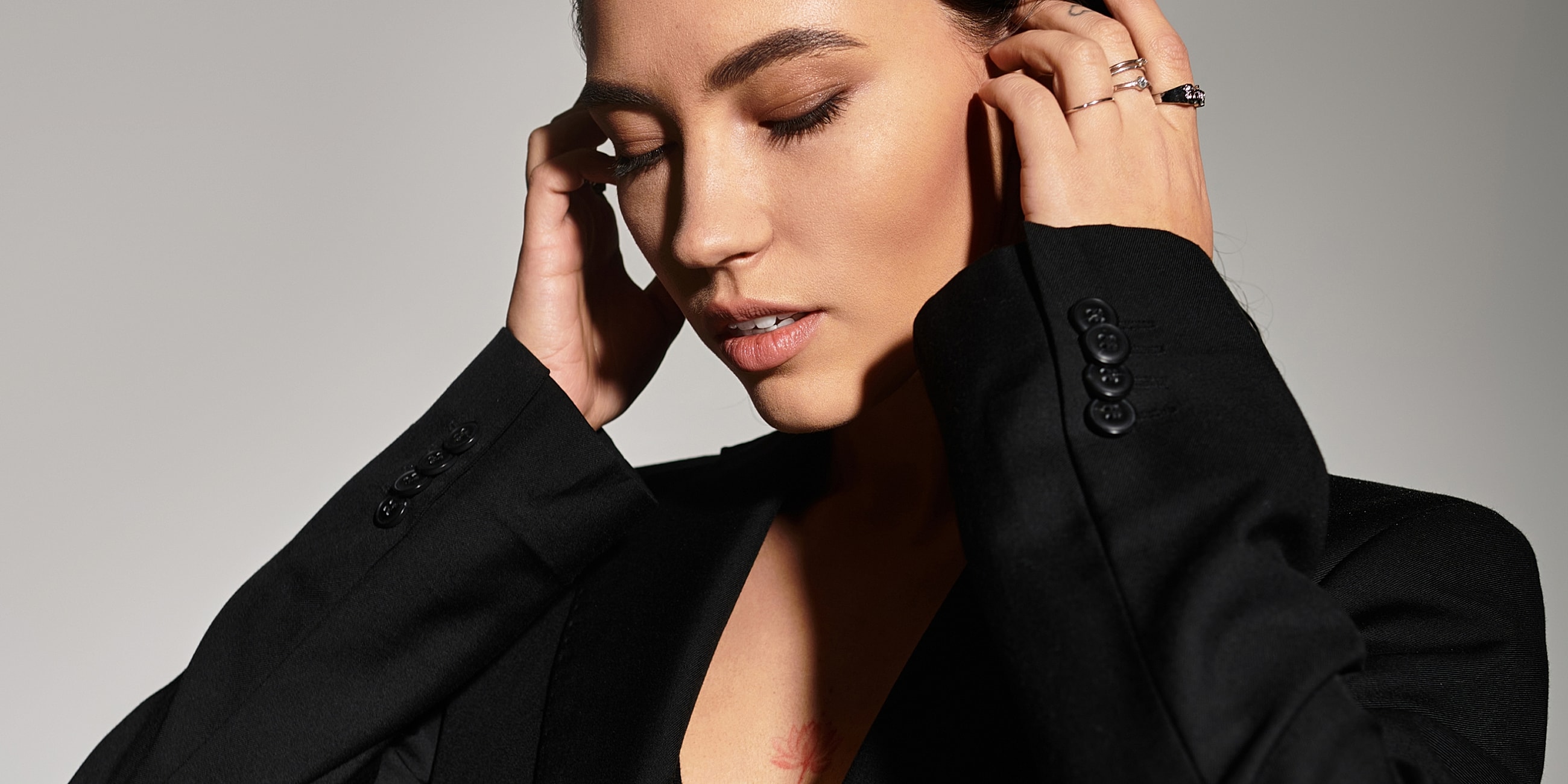 Model in black blazer, eyes closed, serene expression.